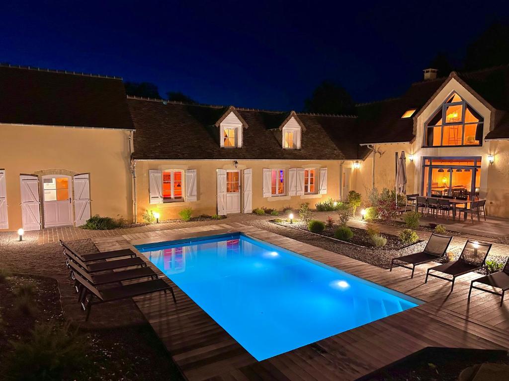 a swimming pool in front of a house at night at Gîte du Soleil dans la Ruelle - Les Hirondelles in Yvré-lʼÉvêque