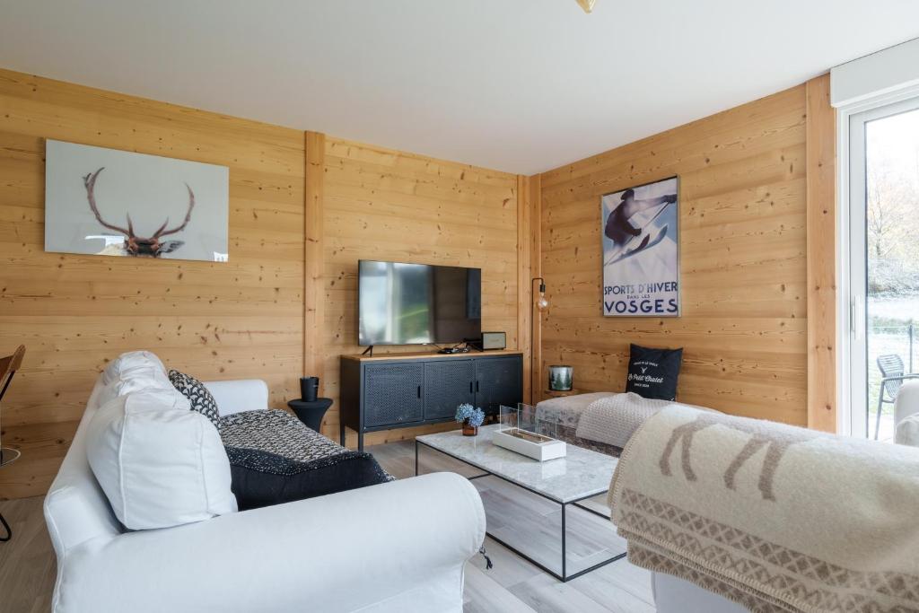 a living room with two white couches and a tv at Le Petit Chalet - Vue montagne in Le Tholy