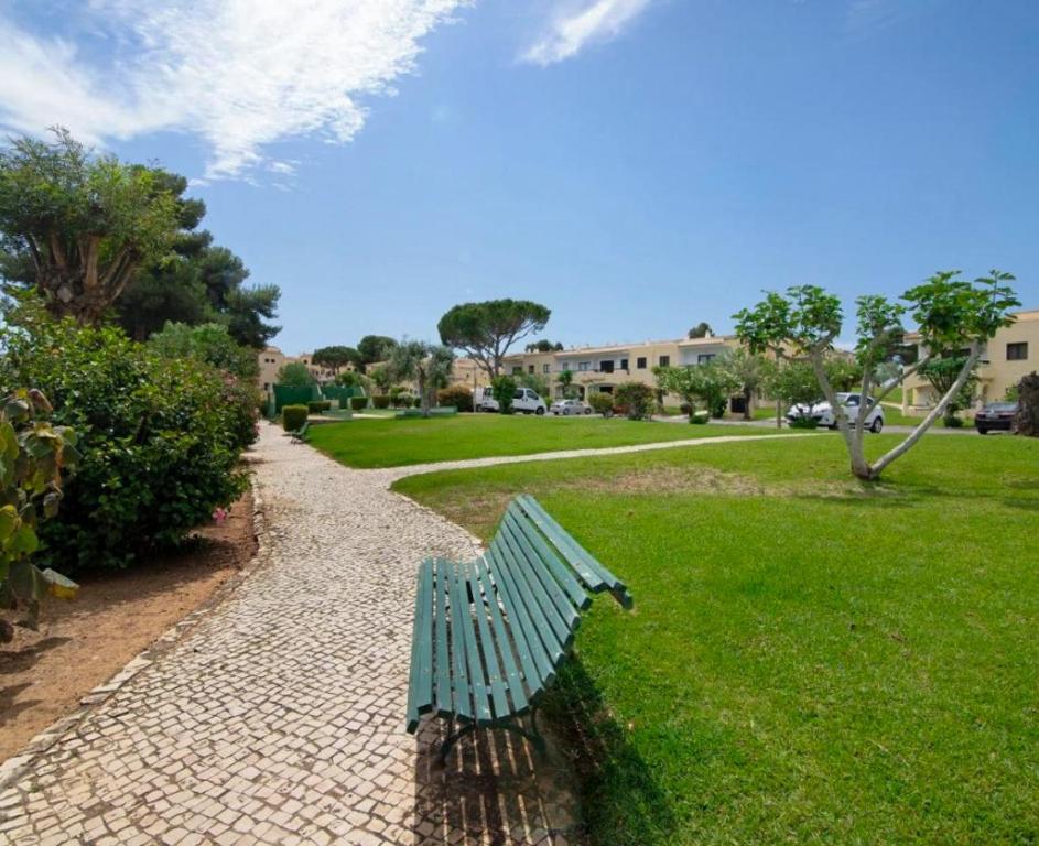 um banco verde de parque sentado num caminho de tijolos em The Green House em Alvor