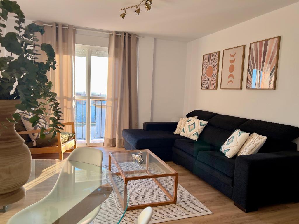 - un salon avec un canapé noir et une table en verre dans l'établissement Apartamento Con Vistas A La Bahía, à Puerto Real