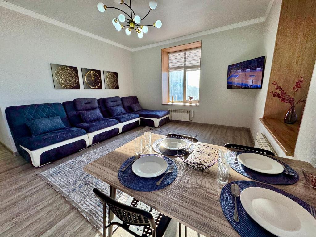 Una sala de estar con una mesa y un sofá azul. en A-Six Apartament, ЖК Arman kala, en Karagandá