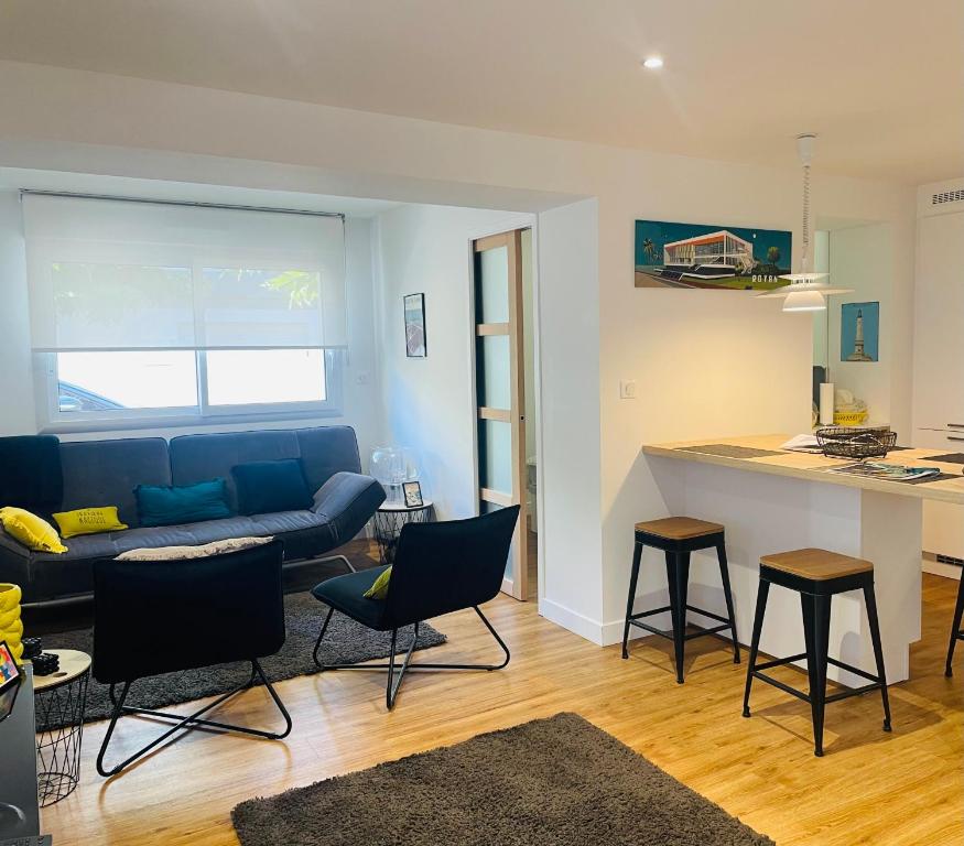 un salon avec un canapé bleu et une cuisine dans l'établissement L’Auguste - Appartement Terrasse, 450m de la plage, à Royan