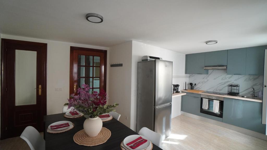 Una cocina con una mesa y un refrigerador de acero inoxidable. en A Xanota, en Combarro