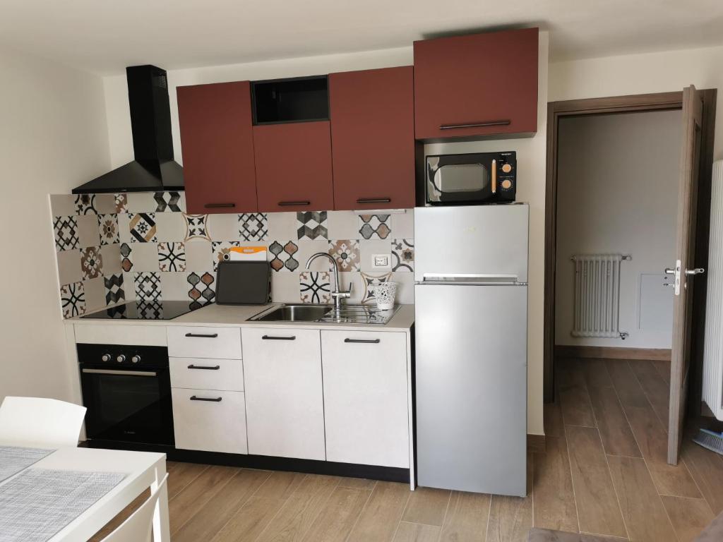 a kitchen with white cabinets and a white refrigerator at Casa vacanze Angeli Custodi in Baselga di Pinè