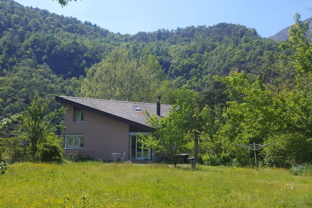 a house in a field with mountains in the background at casa ad Avegno con 1500mq di giardino in Avegno
