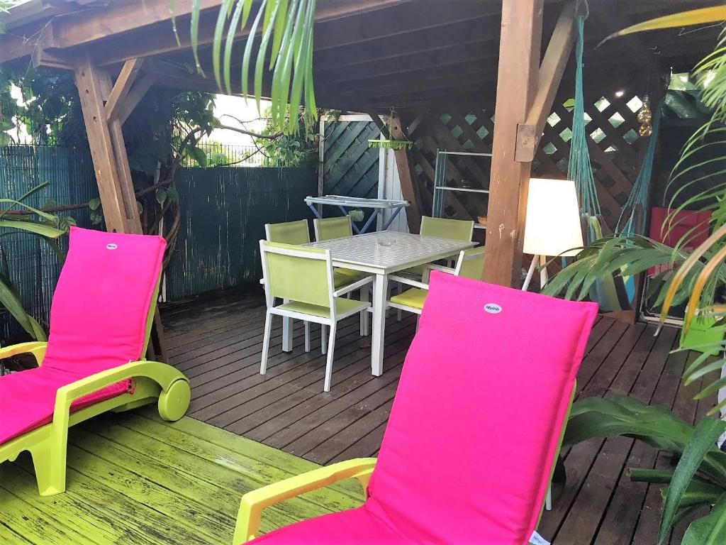 patio con sedie rosa e tavolo su una terrazza di Bungalow confortable à Sainte-Anne, 45 m² avec jardin a Sainte-Anne