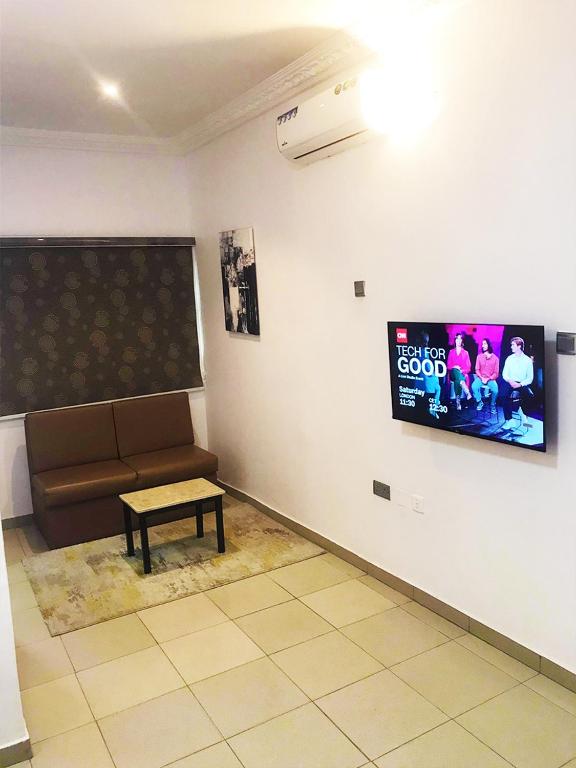 a waiting room with a couch and a tv at Ringruby Hotel, Sangotedo in Sangotedo