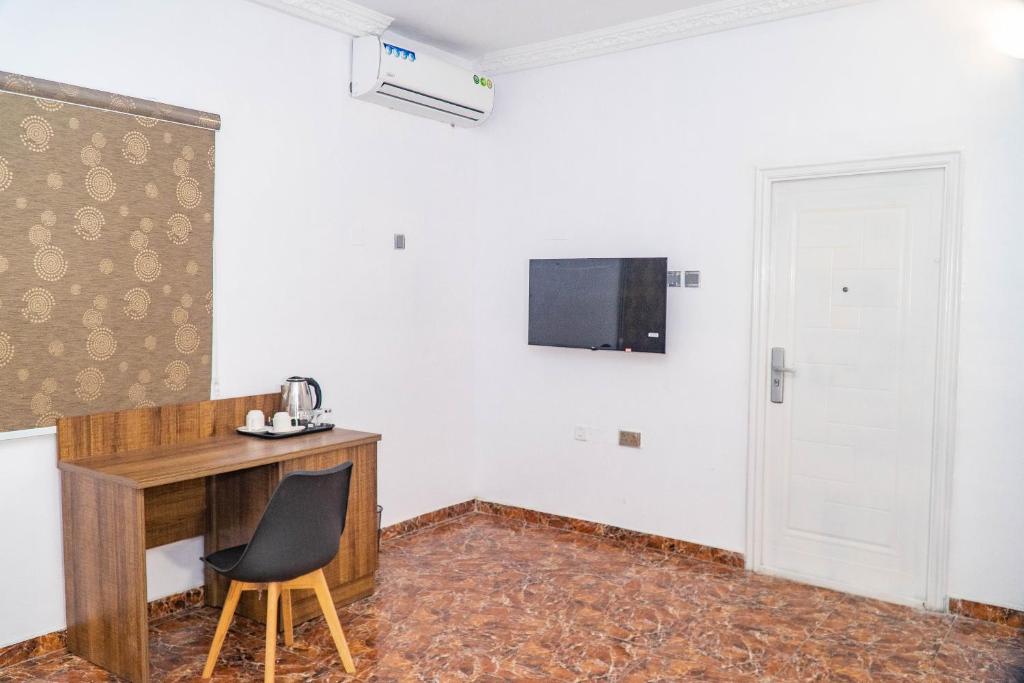 a room with a desk and a television on the wall at Ringruby Hotel, Sangotedo in Sangotedo
