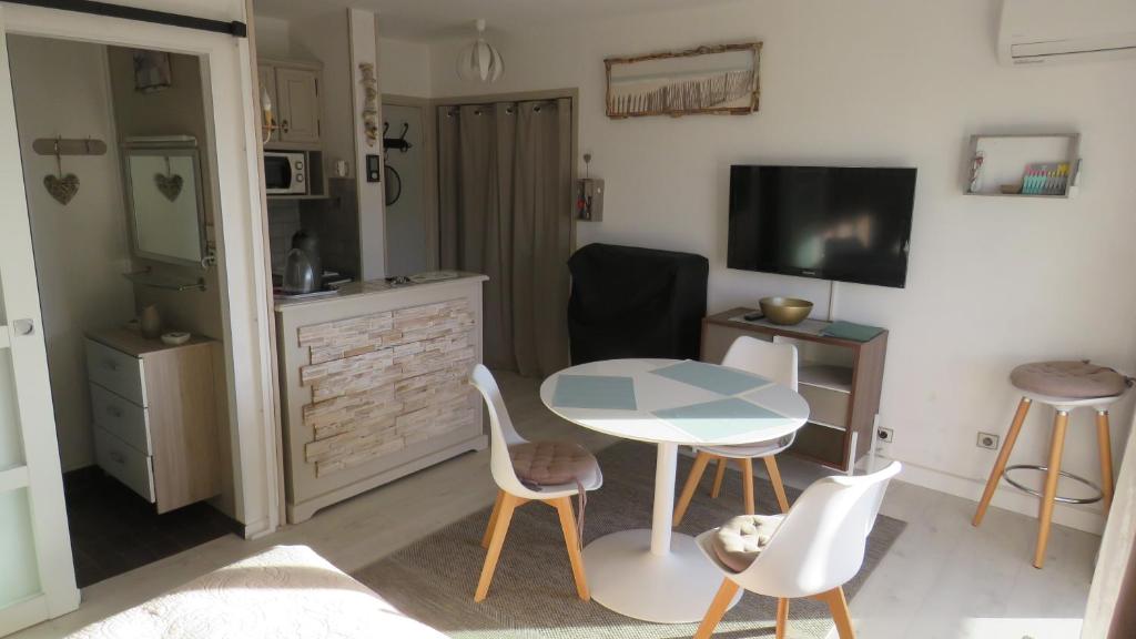 un salon avec une table, des chaises et une télévision dans l'établissement studio cosy avec parking 100m plage, à Fréjus
