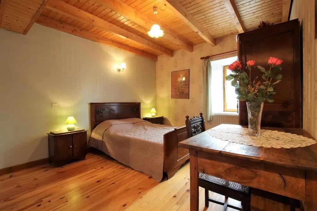 a bedroom with a bed and a table with flowers on it at Charmante maison à la campagne près d'une ferme in Saint-Cirgues