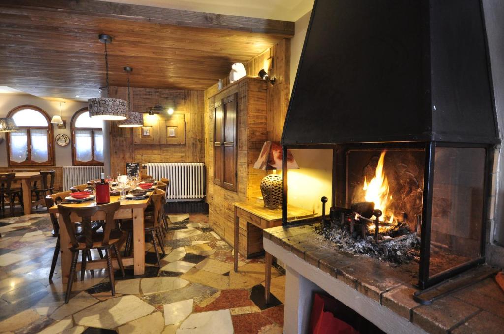 - une cheminée dans une pièce avec une table et une salle à manger dans l'établissement Le Passe Montagne, à Saint-Chaffrey