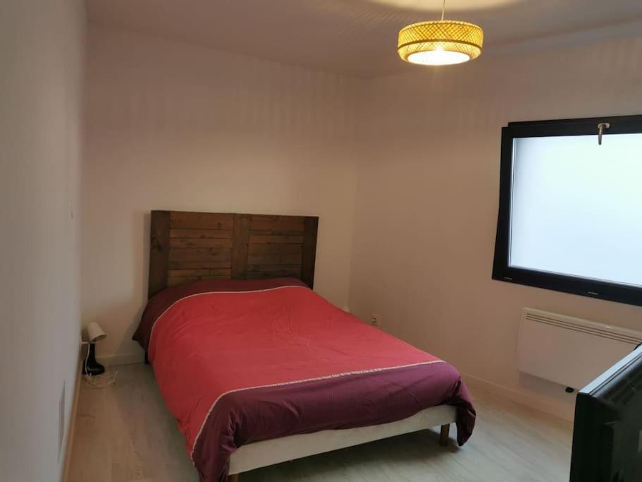 - une chambre avec un lit rouge et un grand écran dans l'établissement Studio RDC, à Loriol-sur-Drôme