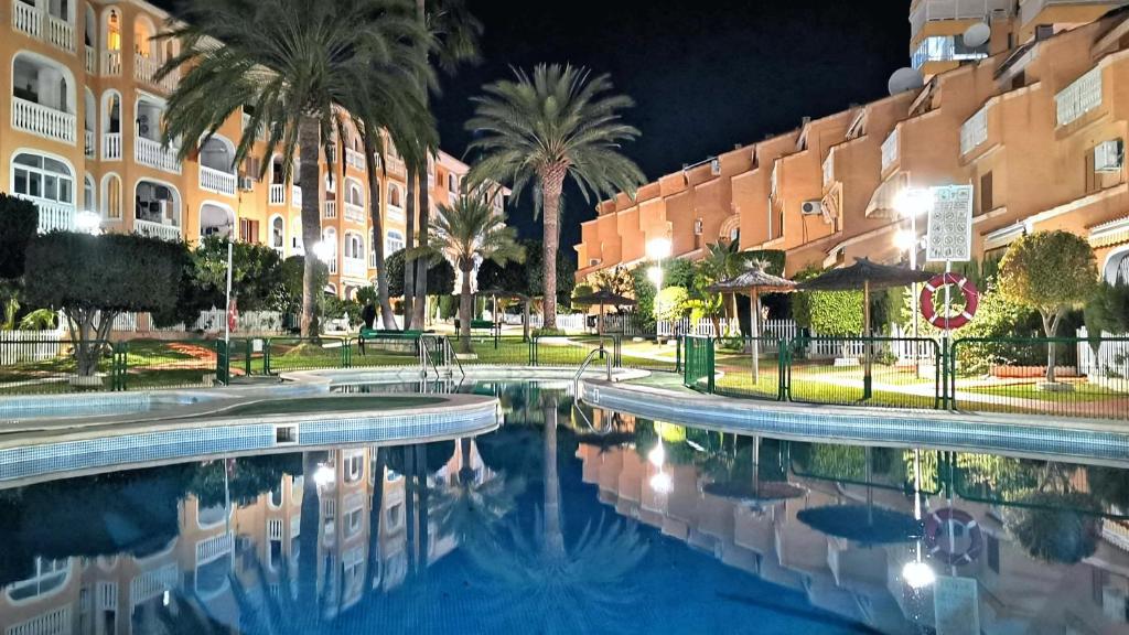 a swimming pool in front of a building at night at La Pla House in El Campello
