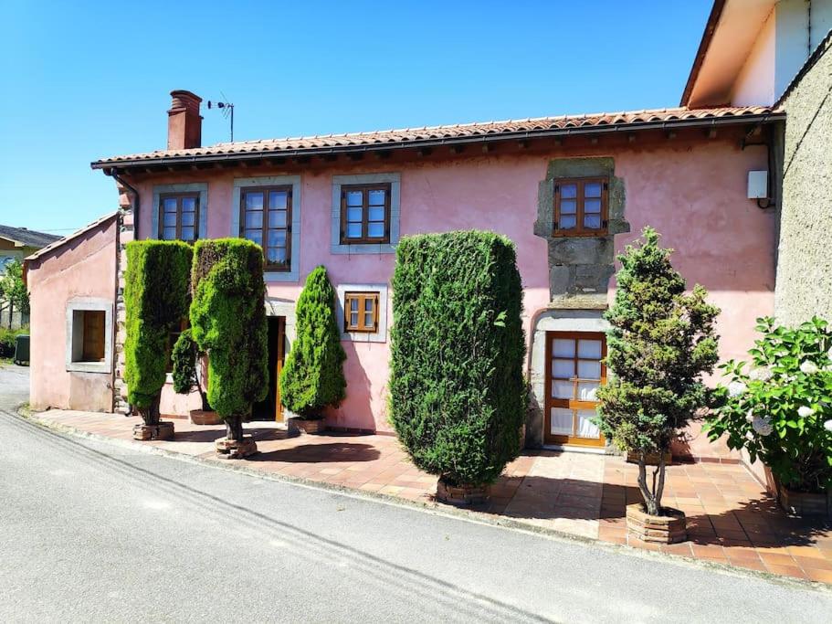 ein rosafarbenes Haus mit Bäumen vor einer Straße in der Unterkunft Espaciosa casa rural reformada junto al mar in Albuerne