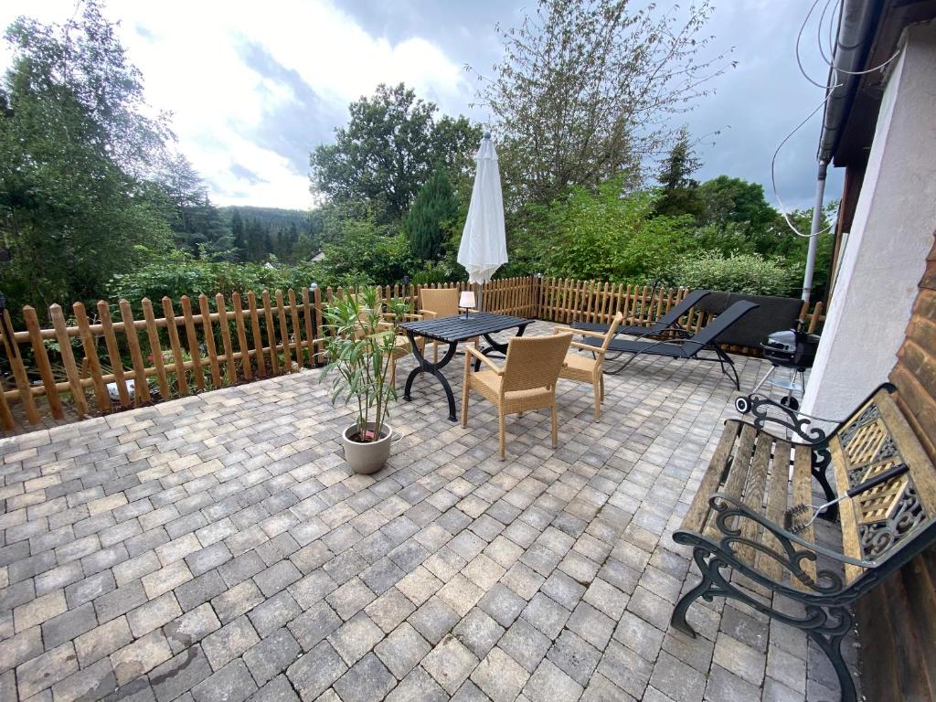 a patio with a table and chairs and an umbrella at EIFELCOTTAGE Zaunkönig in Ulmen