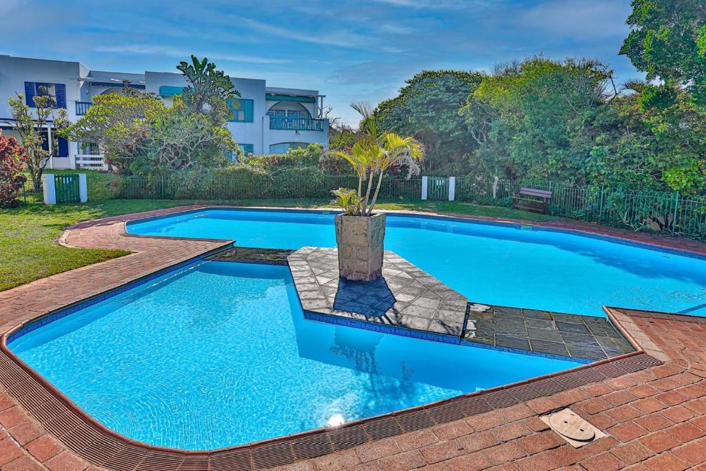 a swimming pool in a yard with a house in the background at 31 Akrotiri, Santorini, Ballito in Ballito