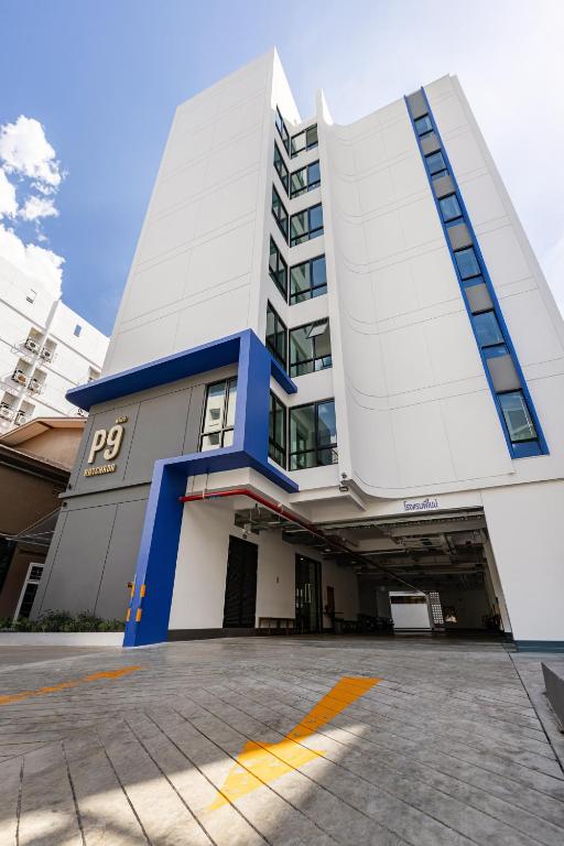 a white and blue building with a parking lot at P9 Ratchada Hotel in Bangkok