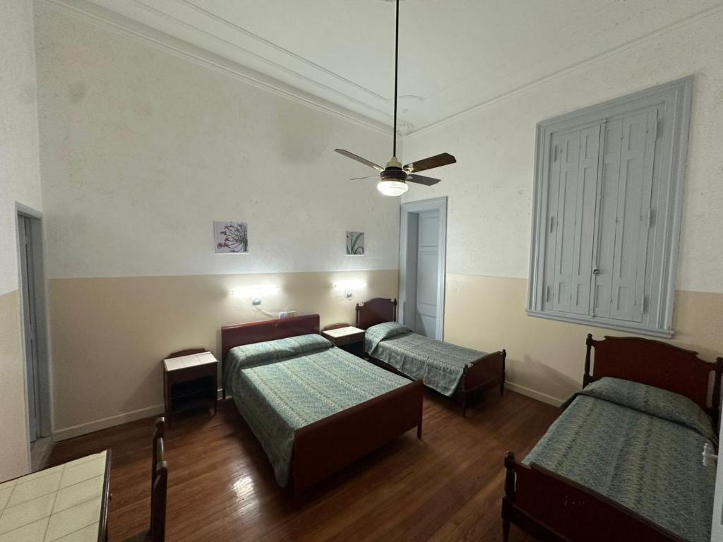 a room with two beds and a ceiling fan at Recoleta 680 in Buenos Aires