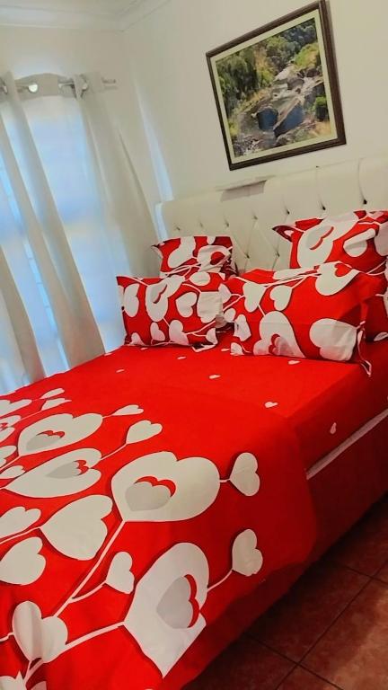 a bed with a red blanket with white cows on it at Hussein accommodation in Cape Town