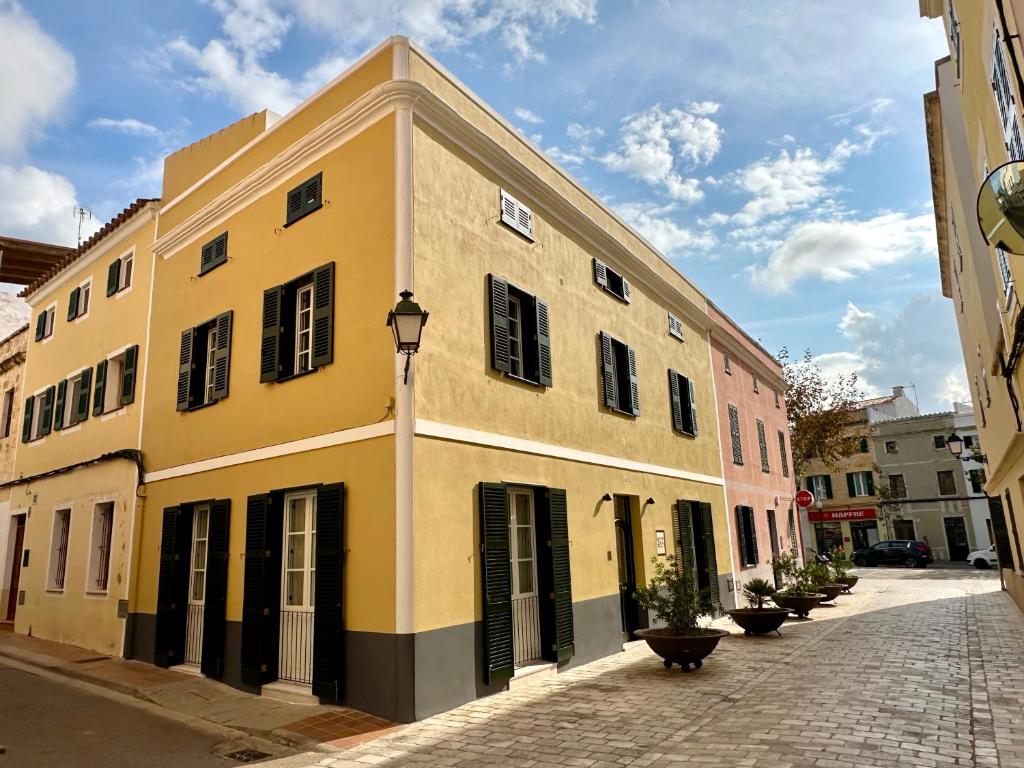 een geel gebouw met zwarte luiken op een straat bij SetBlaus Boutique Hotel in Ciutadella