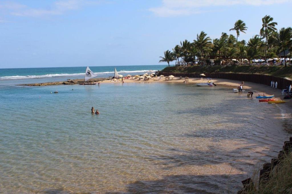 una playa con un grupo de personas en el agua en Nannai Residence - Flat em Muro Alto, en Porto de Galinhas