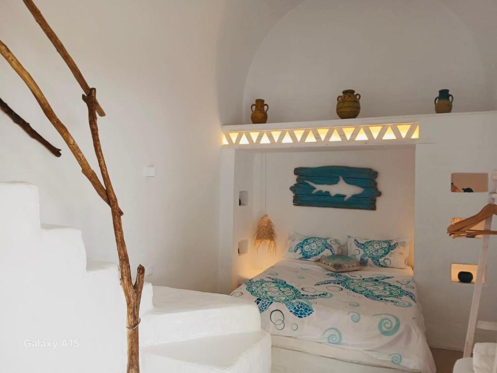 a white bedroom with a bed with blue and white sheets at Dar El Mahdia by Daldoul in Mahdia