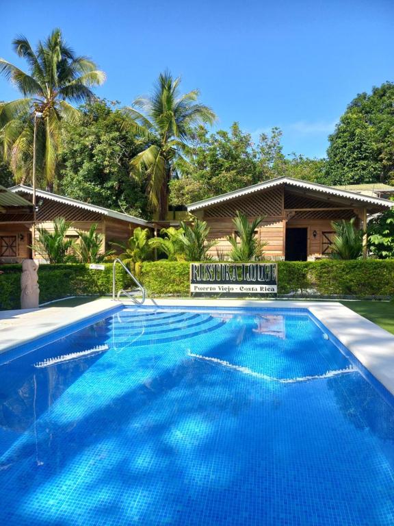 a large blue swimming pool in front of a house at Rustika Logde in Puerto Viejo