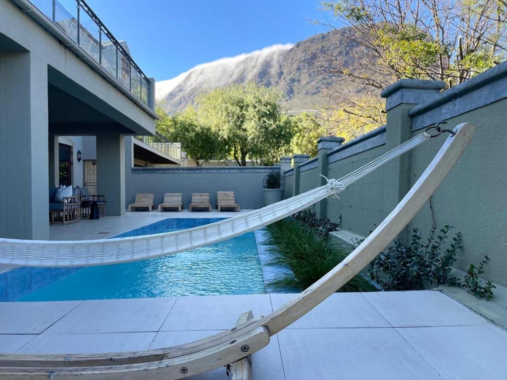 a swimming pool with a hammock next to a house at Calais Guest House in Franschhoek