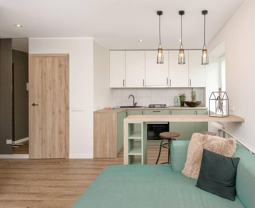 a kitchen and a living room with a couch and a table at Sunshine apartamentai in Alytus