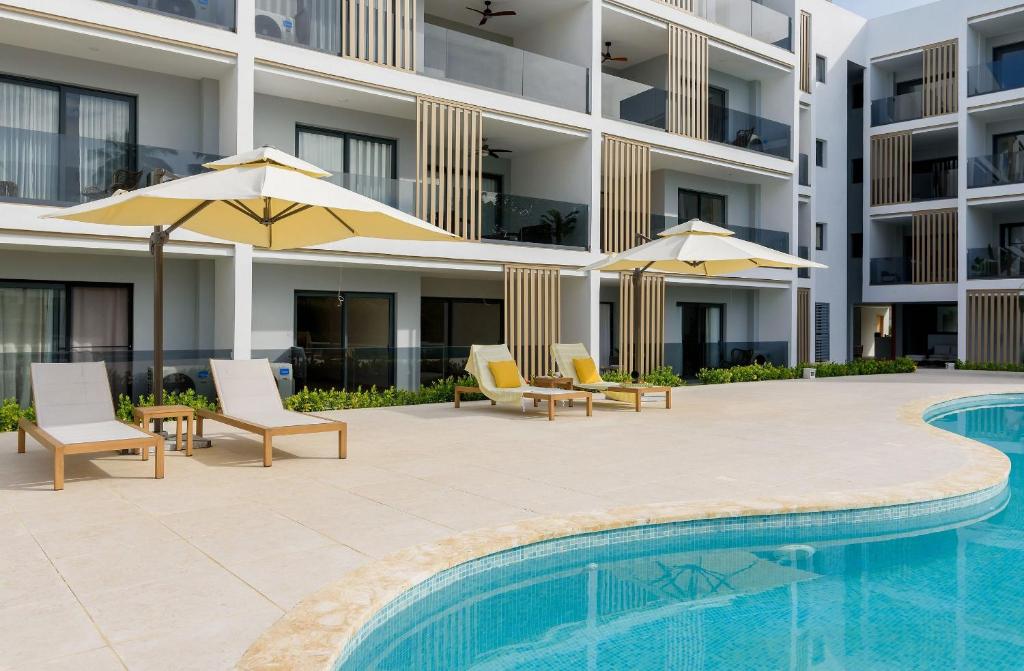 a swimming pool with chairs and umbrellas next to a building at Sausalito | Pool View Retreat in Punta Cana