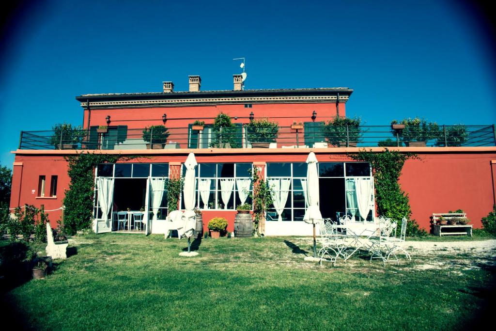 ein großes rotes Gebäude mit einem Hof davor in der Unterkunft Tenuta Santini in Coriano