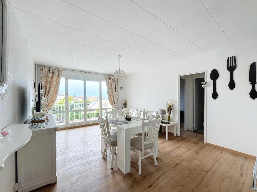 une cuisine et une salle à manger avec une table et des chaises dans l'établissement L'air marin, à Ouistreham