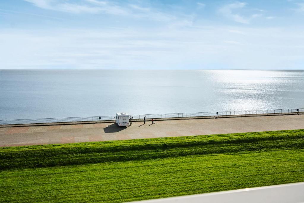 a van parked on a sidewalk next to the ocean at Strand-Penthouse, 128 qm, Maisonette, Parkplatz in Wilhelmshaven