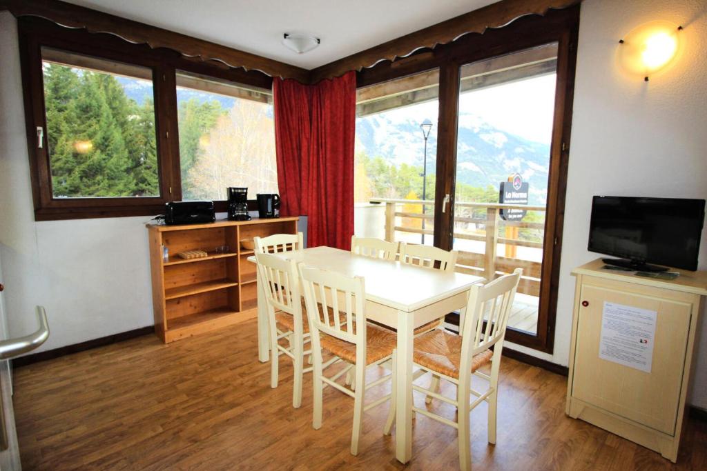 une salle à manger avec une table, des chaises et une télévision dans l'établissement Résidence Les Balcons De La Vanoise - LES BALCONS DE LA VANOISE-BV102 MAE-9031, à Villarodin-Bourget