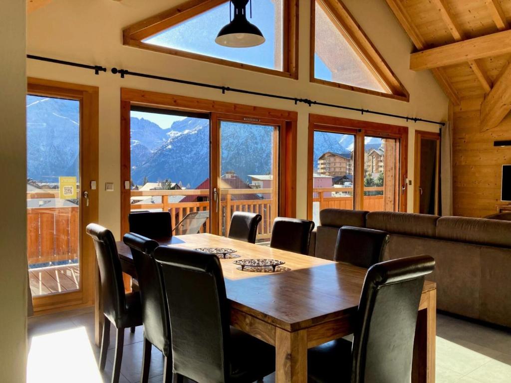 une salle à manger avec une table, des chaises et des fenêtres dans l'établissement La Residence - Appartement La Résidence MAE-9501, à Vénosc