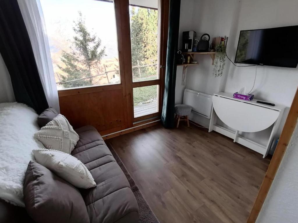 un salon avec un canapé et une grande fenêtre dans l'établissement Résidence Le Chanteloup - Studio fonctionnel pied des pistes MAE-9431, à Aime La Plagne