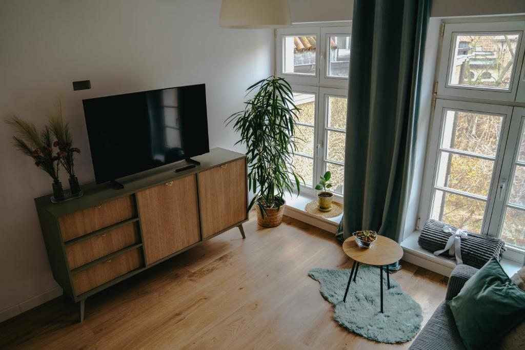 a living room with a flat screen tv on a dresser at Szeroka 32 Studio in Toruń
