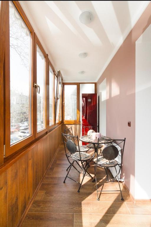 a dining room with a table and chairs and windows at Deribasovskay street apartments in Odesa