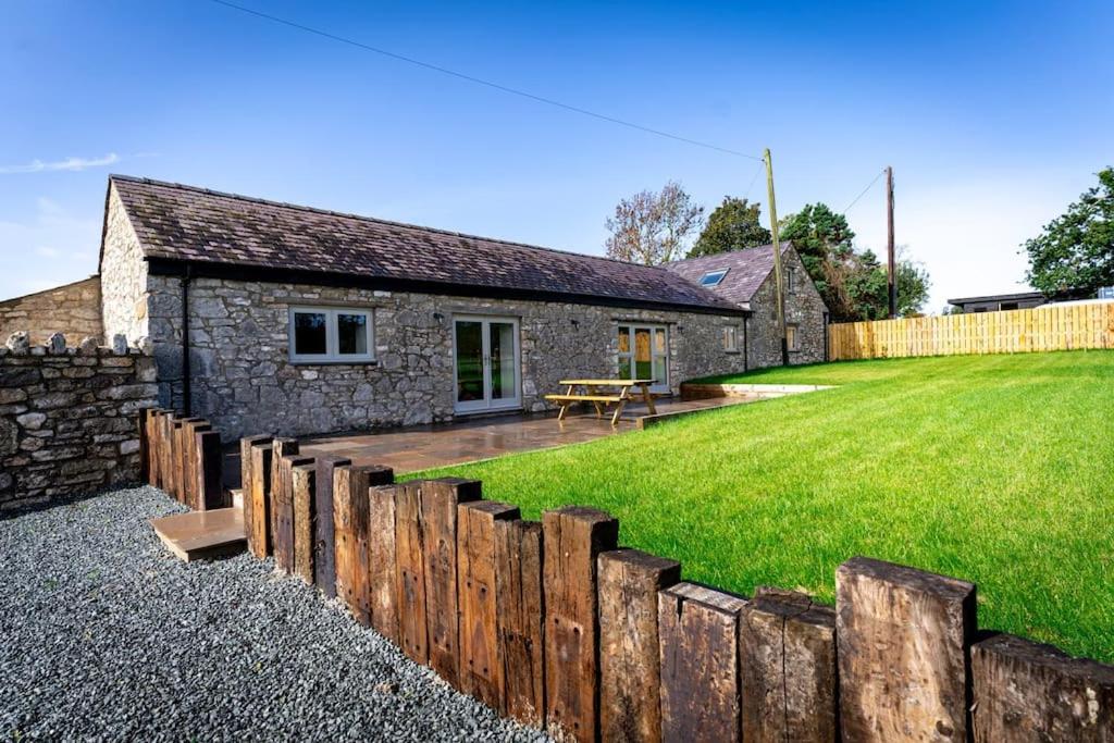 a stone cottage with a wooden fence in front of it at Long Barn, seaside cosy cottage for 8 in Beaumaris