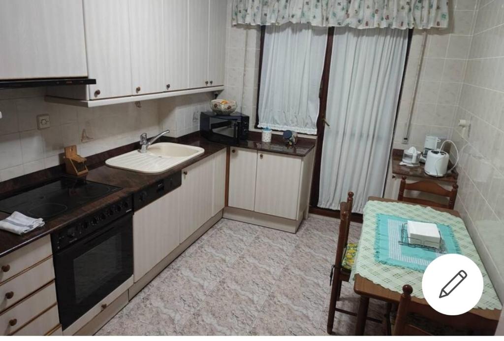 Una pequeña cocina con fregadero y estufa. horno superior en Secuoya, en Cabezón de la Sal