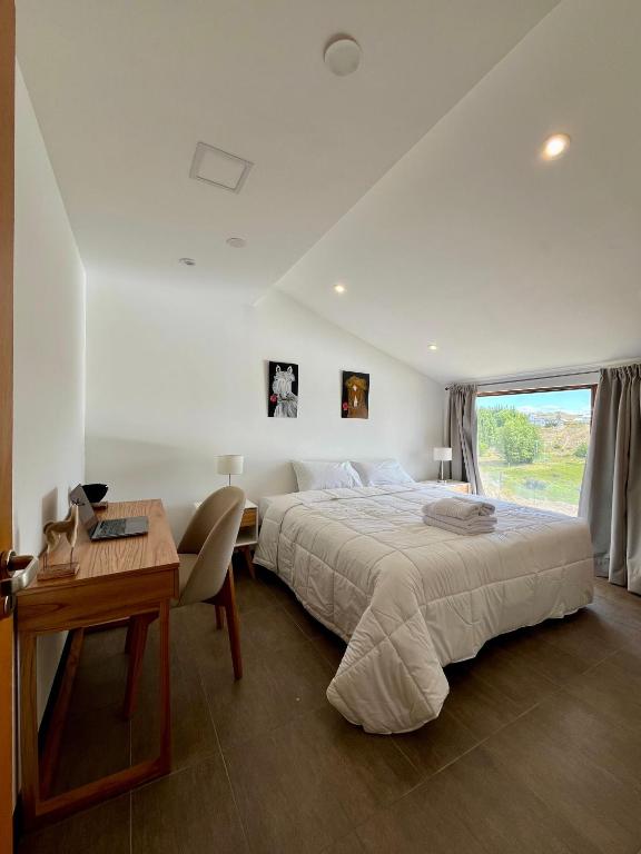 a bedroom with a bed and a desk and a window at Haven Patagonia in El Calafate