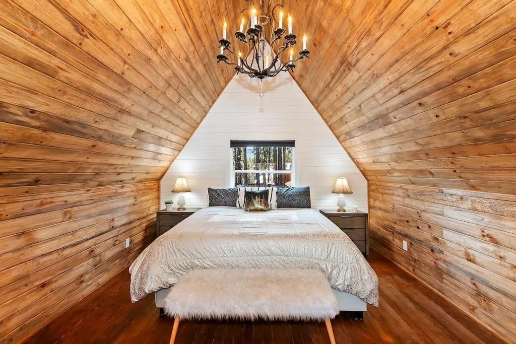 ein Schlafzimmer mit einem großen Bett an einer Holzwand in der Unterkunft NEW Cozy Coy Cabin with Hot Tub & AC in Big Bear City