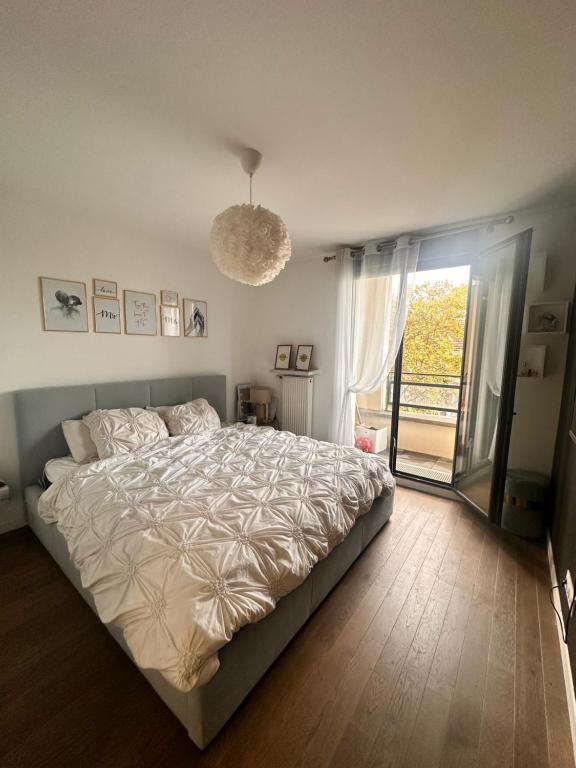 une chambre avec un grand lit et une grande fenêtre dans l'établissement Central, à Colombes