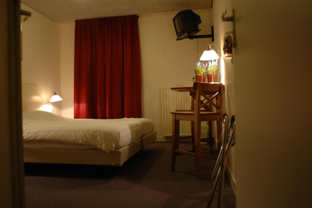 1 dormitorio con cama, mesa y cortina roja en HCR Teernstra, en Balk