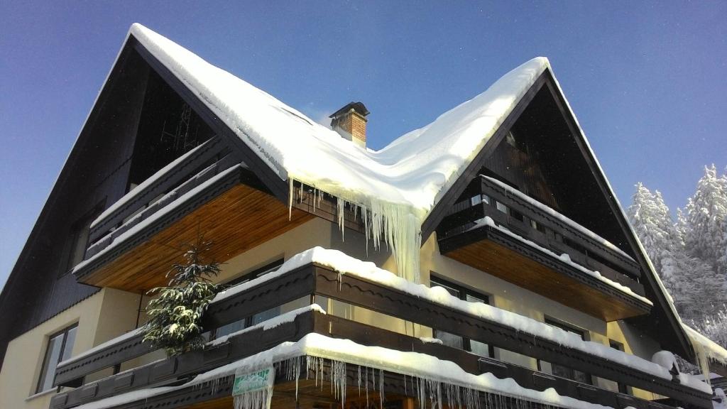 a building covered in snow with icicles on it at Apartmán Šírovi in Benecko