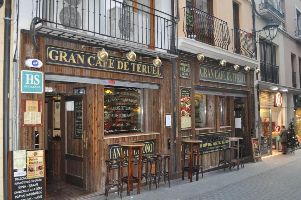 un bar con sgabelli di fronte a un edificio di Hostal Alcazaba a Teruel