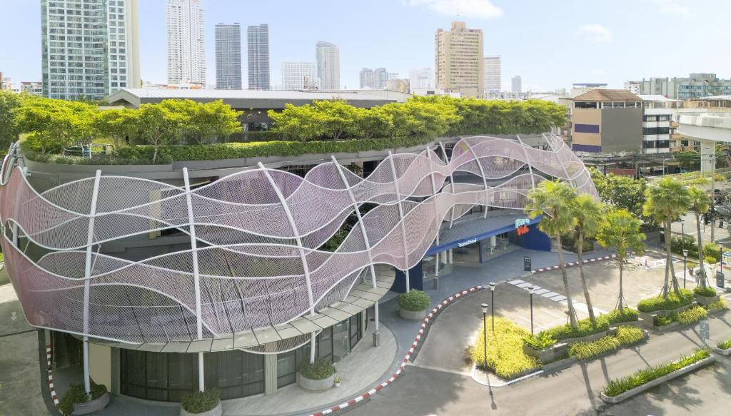 a building with a purple slide in a city at Riva Vibe Hotel Bangkok by PCL in Bangkok