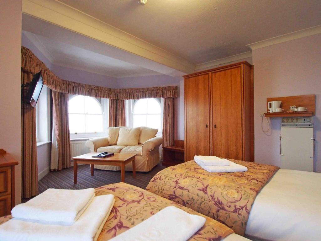 a hotel room with two beds and a couch at The Chatsworth Hotel in Worthing