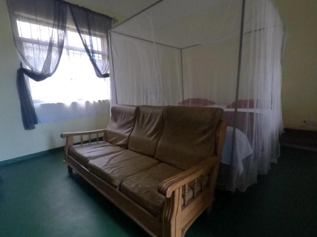 a couch sitting in a room with a window at East Homestay in Boma la Ngombe