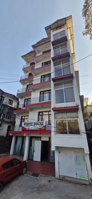 um edifício com um carro vermelho estacionado em frente dele em Hotel White Villa em Shimla